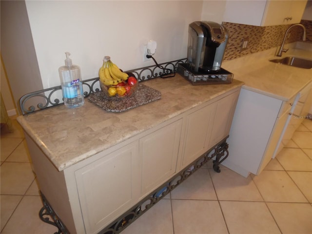 kitchen featuring sink, light stone counters, light tile patterned flooring, kitchen peninsula, and white cabinets