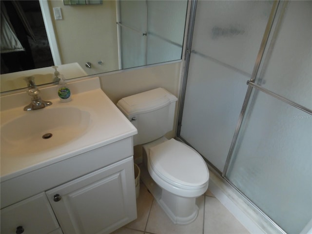 bathroom with tile patterned flooring, vanity, toilet, and a shower with shower door