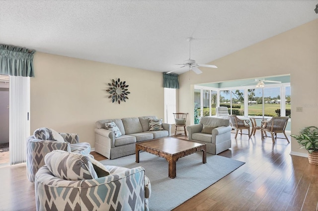 living room with a textured ceiling, hardwood / wood-style flooring, ceiling fan, and lofted ceiling