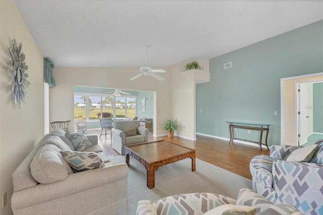 living room with ceiling fan, wood-type flooring, and vaulted ceiling