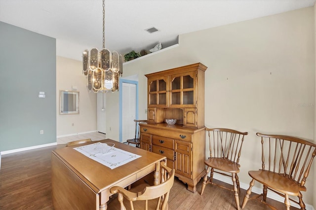 dining area with hardwood / wood-style floors and a chandelier