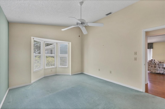 carpeted spare room with vaulted ceiling, ceiling fan, and a textured ceiling