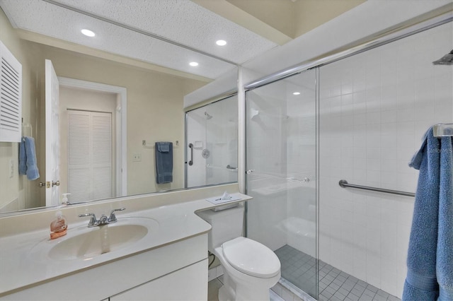 bathroom with vanity, toilet, a shower with shower door, and a textured ceiling