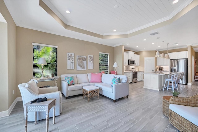 living room with light hardwood / wood-style floors, sink, crown molding, and a raised ceiling