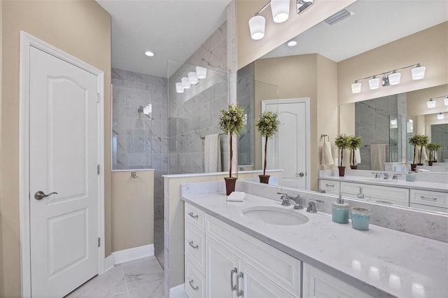 bathroom with tiled shower and vanity