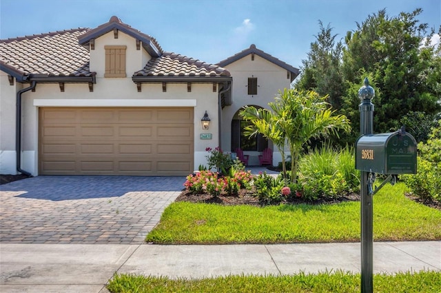 mediterranean / spanish home featuring a garage and a front yard