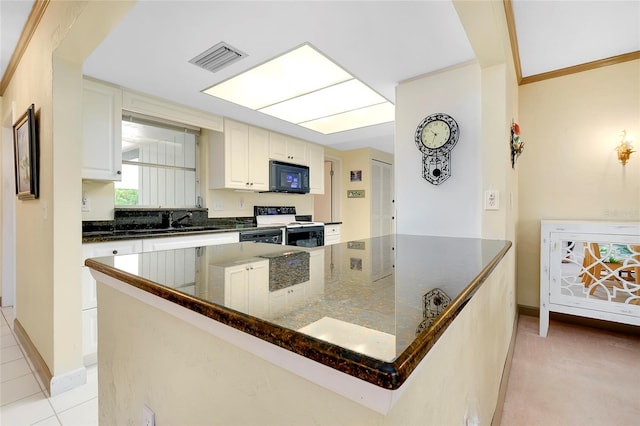 kitchen with electric stove, dark stone countertops, white cabinets, light tile patterned floors, and a spacious island