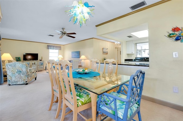 carpeted dining area featuring ceiling fan with notable chandelier and crown molding