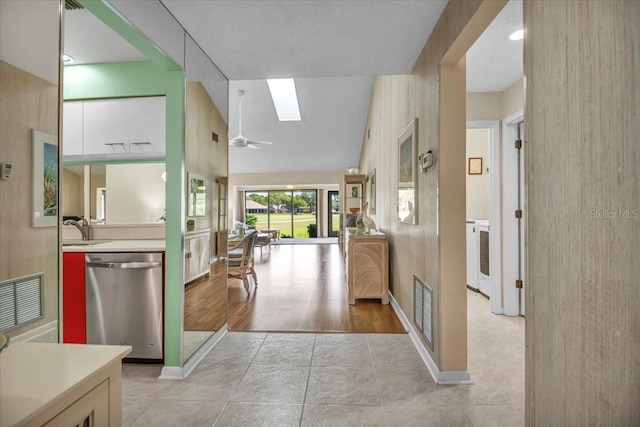 hall with sink, light wood-type flooring, and vaulted ceiling with skylight