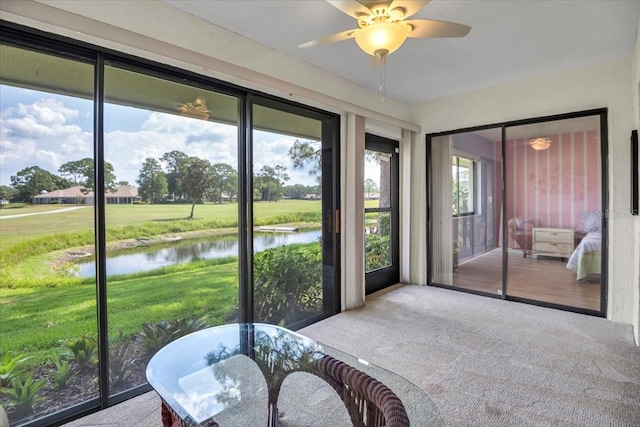 sunroom / solarium featuring ceiling fan and a water view