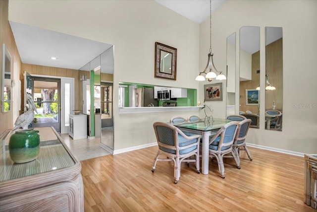 dining area featuring high vaulted ceiling, a notable chandelier, and light wood-type flooring