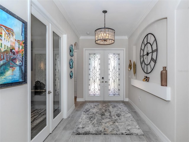 entryway featuring an inviting chandelier, crown molding, and french doors