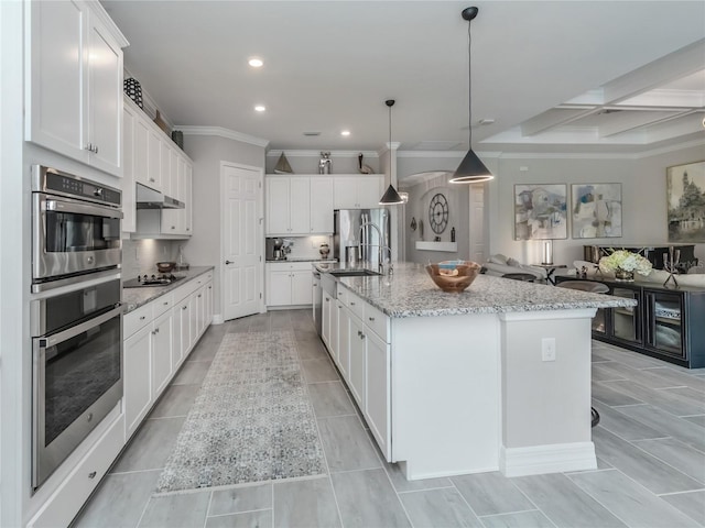 kitchen featuring decorative light fixtures, a spacious island, white cabinets, and light stone countertops