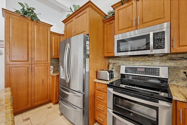 kitchen with light stone counters, brown cabinetry, tasteful backsplash, and appliances with stainless steel finishes