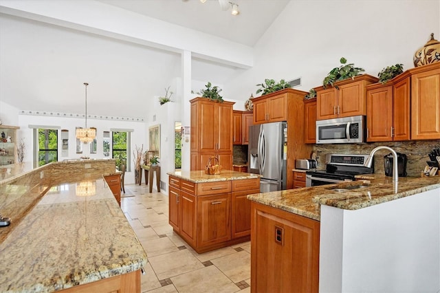 kitchen featuring light stone counters, decorative backsplash, appliances with stainless steel finishes, and brown cabinetry