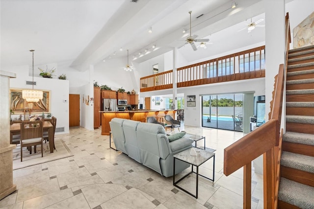 living area with visible vents, beam ceiling, high vaulted ceiling, ceiling fan with notable chandelier, and stairway