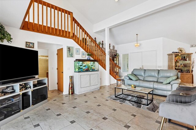 living room with beamed ceiling, high vaulted ceiling, and stairs