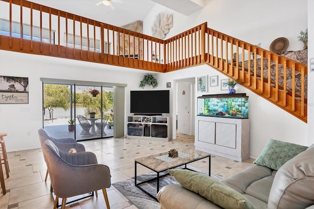 living area with stairs, baseboards, a towering ceiling, and ceiling fan