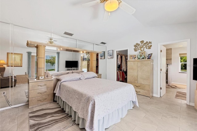 bedroom with visible vents, a walk in closet, a closet, baseboards, and ceiling fan