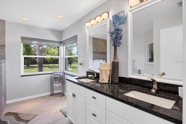 bathroom with double vanity, baseboards, visible vents, and a sink