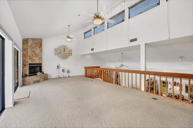 interior space with a stone fireplace, carpet flooring, visible vents, and a wealth of natural light