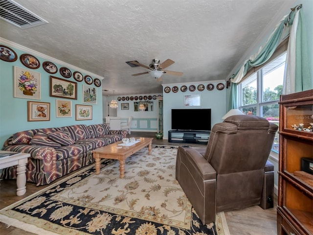 living room with a textured ceiling, ceiling fan, and ornamental molding