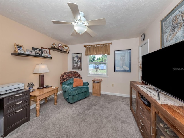 living area with ceiling fan, light colored carpet, and a textured ceiling