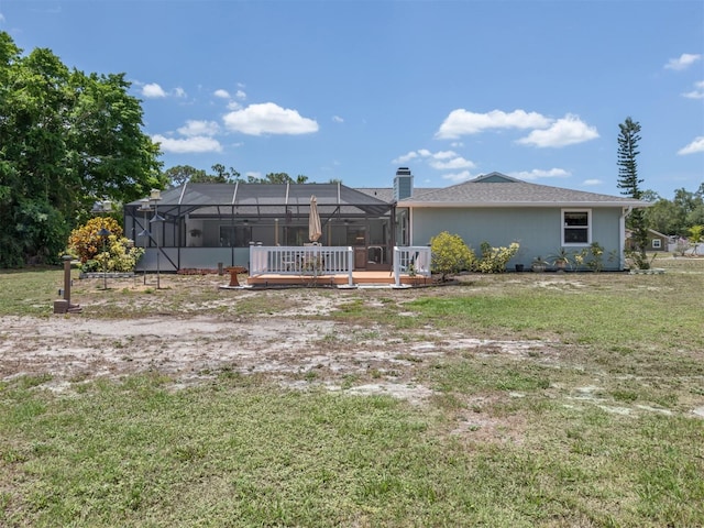 back of house with glass enclosure and a yard