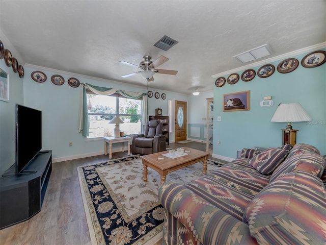 living room featuring crown molding, ceiling fan, wood-type flooring, and a textured ceiling