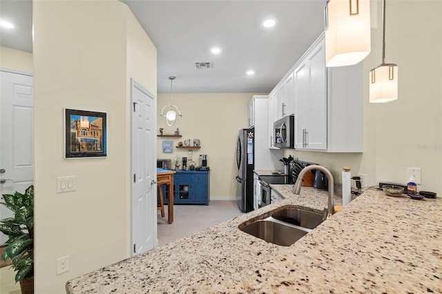 kitchen featuring white cabinetry, appliances with stainless steel finishes, pendant lighting, light stone counters, and sink