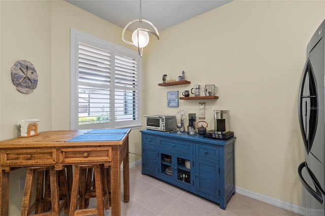 kitchen featuring decorative light fixtures, black refrigerator, butcher block counters, light tile patterned floors, and blue cabinets