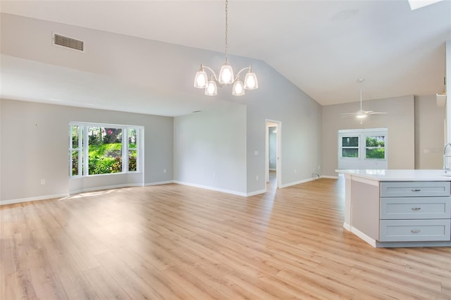 interior space featuring ceiling fan with notable chandelier, light hardwood / wood-style floors, and vaulted ceiling