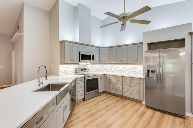 kitchen featuring a high ceiling, backsplash, stainless steel appliances, and sink