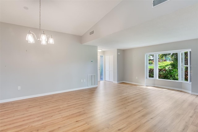 spare room with a chandelier, light hardwood / wood-style floors, and vaulted ceiling