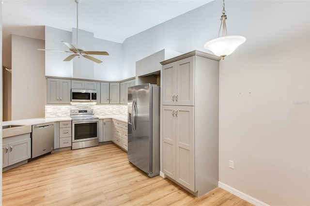 kitchen featuring decorative backsplash, appliances with stainless steel finishes, hanging light fixtures, and gray cabinetry