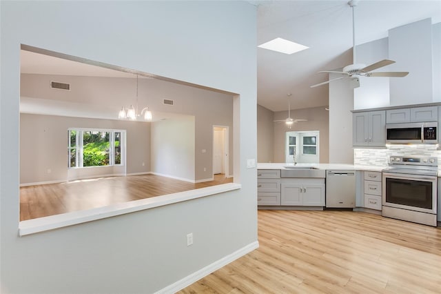 kitchen with tasteful backsplash, gray cabinetry, high vaulted ceiling, and stainless steel appliances