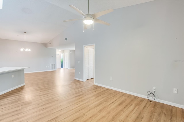 spare room with light hardwood / wood-style flooring, high vaulted ceiling, and ceiling fan with notable chandelier