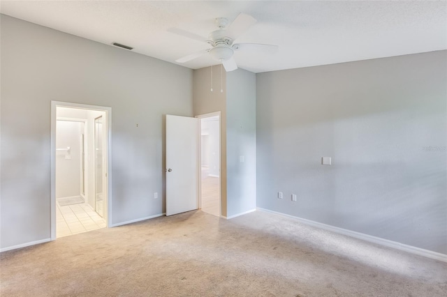 unfurnished bedroom with ceiling fan, light colored carpet, a towering ceiling, and ensuite bathroom