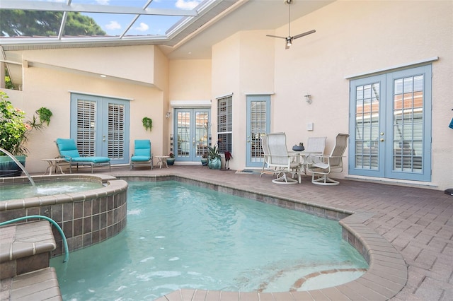 view of pool featuring glass enclosure, french doors, pool water feature, an in ground hot tub, and a patio