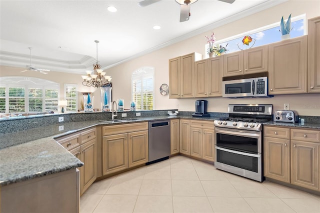 kitchen featuring a chandelier, stainless steel appliances, a wealth of natural light, and dark stone countertops