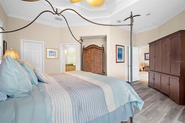 bedroom with ensuite bath, a towering ceiling, light hardwood / wood-style floors, and ornamental molding