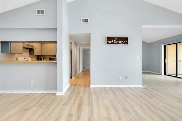 kitchen with range, high vaulted ceiling, and light hardwood / wood-style flooring