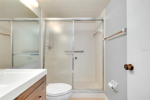 bathroom featuring tile patterned floors, vanity, toilet, and a shower with door