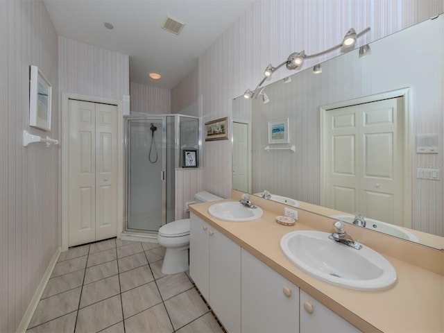 bathroom featuring toilet, vanity, tile patterned floors, and a shower with door