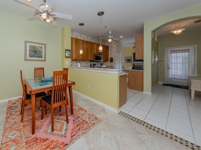 kitchen with ceiling fan, hanging light fixtures, tasteful backsplash, kitchen peninsula, and light tile patterned floors