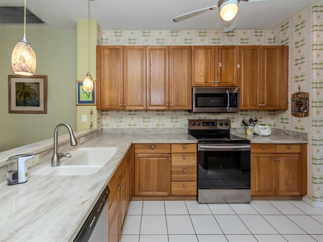 kitchen with sink, hanging light fixtures, ceiling fan, light tile patterned floors, and stainless steel appliances