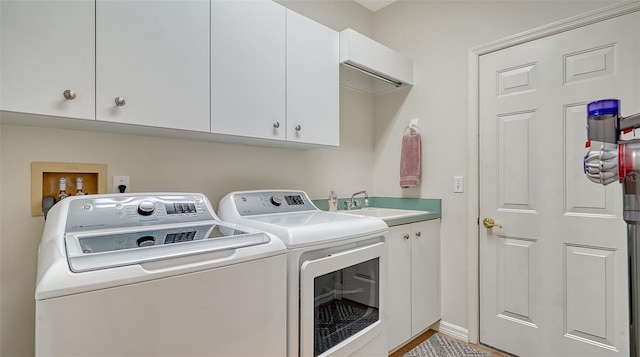 clothes washing area featuring cabinets, sink, and washer and dryer