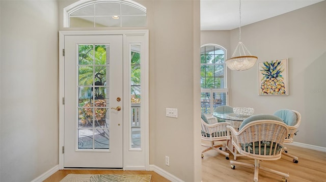 entrance foyer with a notable chandelier, wood finished floors, and baseboards