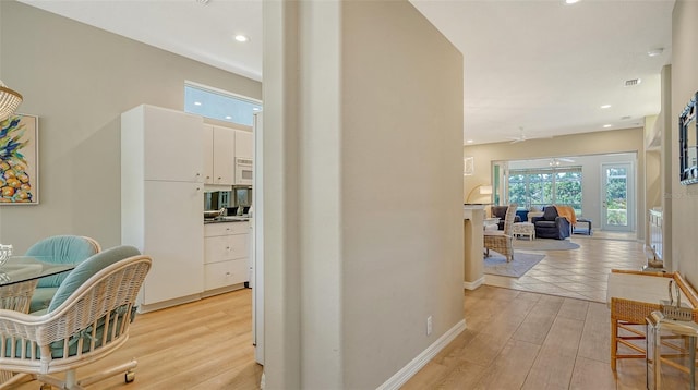 hall featuring light wood-style floors, recessed lighting, visible vents, and baseboards