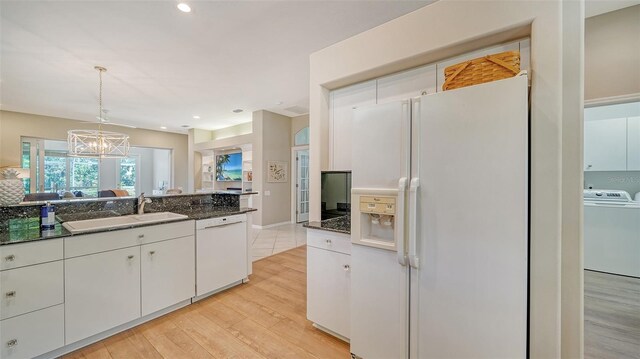 kitchen with pendant lighting, white cabinetry, washer / dryer, sink, and white appliances